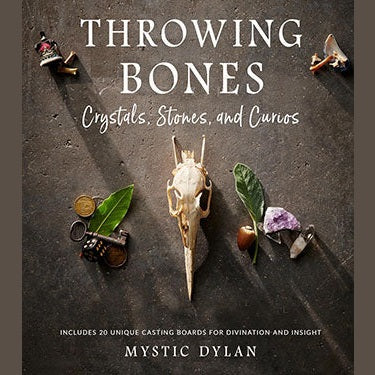 Book cover of "Throwing Bones, Crystals, Stones, & Curios" by Mystic Dylan featuring mystical objects like a skull, crystals, leaves, and trinkets arranged on a dark surface.