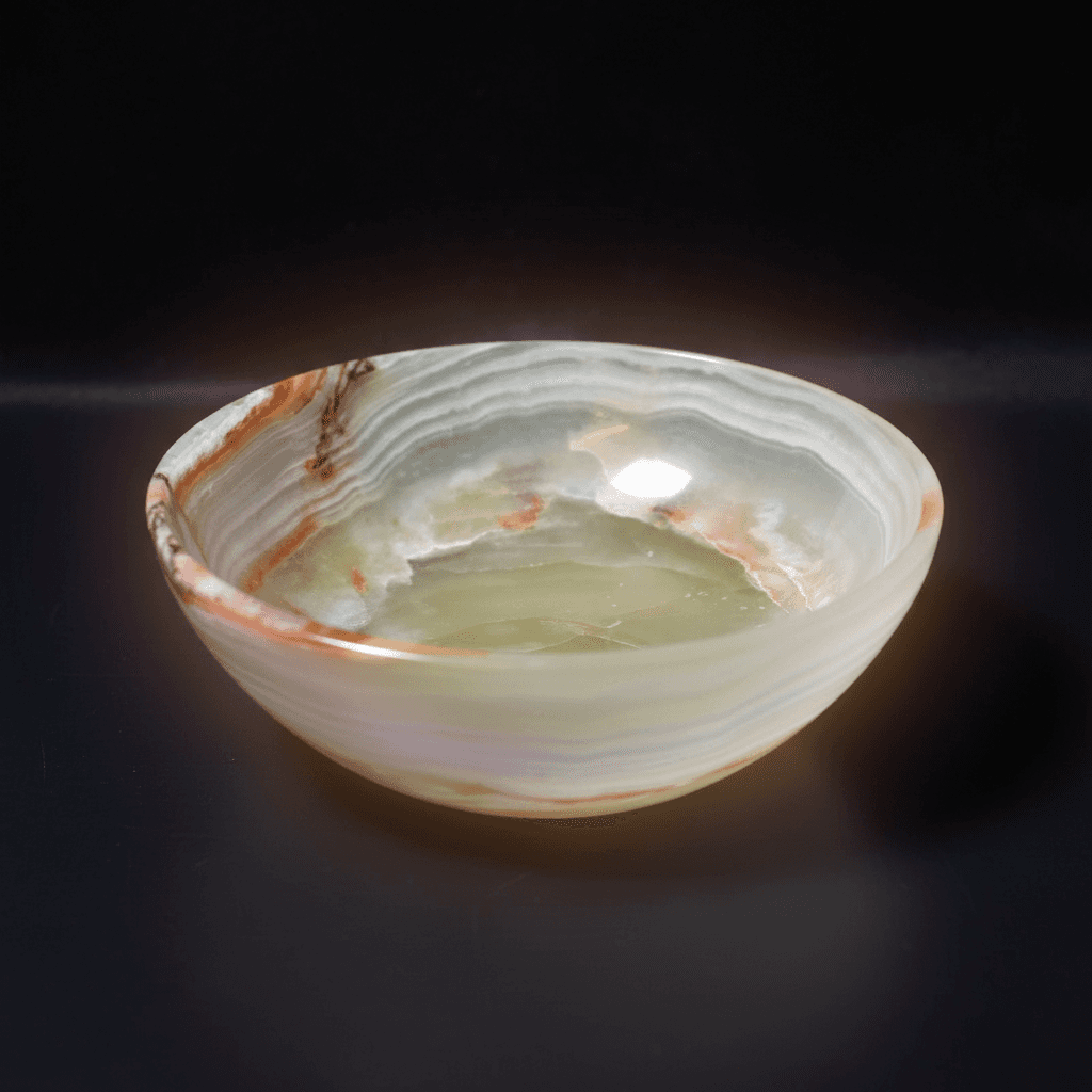 A highly detailed professional studio shot of the Onyx Stone Bowl, captured from a top-down angle with a macro lens at 85mm focal length, emphasizing the smooth, polished surface and deep matte black texture of the onyx. The bowl is set against a subtle, d