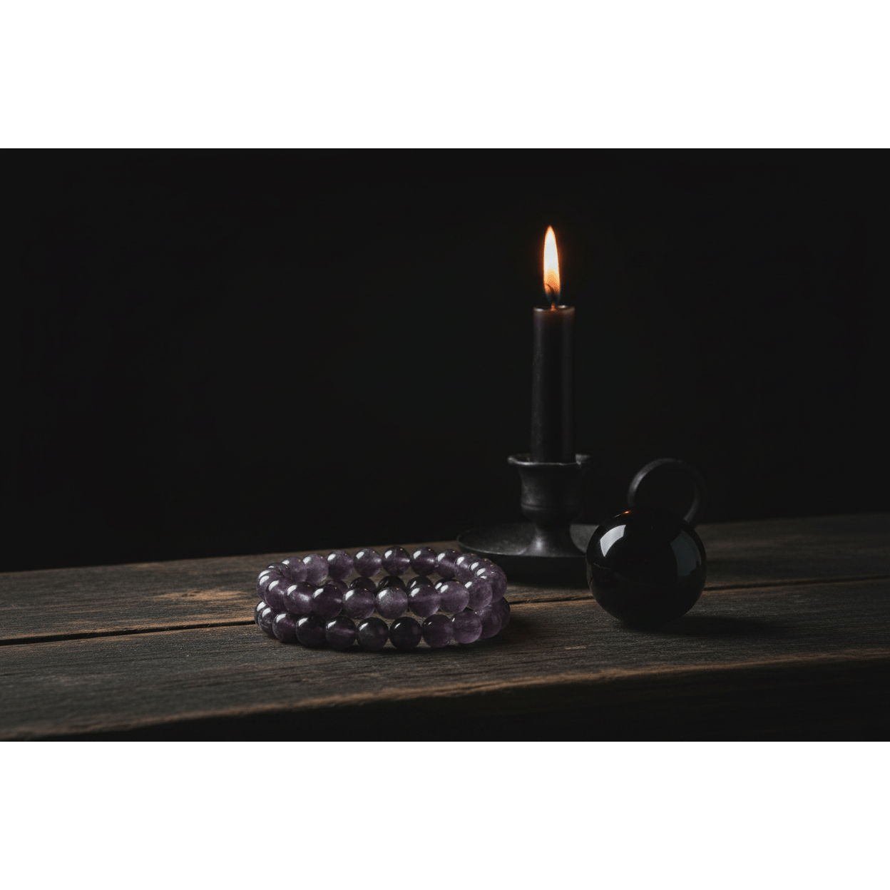 Amethyst bracelet with 8mm muted beads on dark wooden altar beside lit black taper candle and obsidian sphere