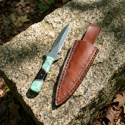 7-inch turquoise and black handled athame in a leather sheath resting on a stone surface outdoors, with natural light emphasizing textures.