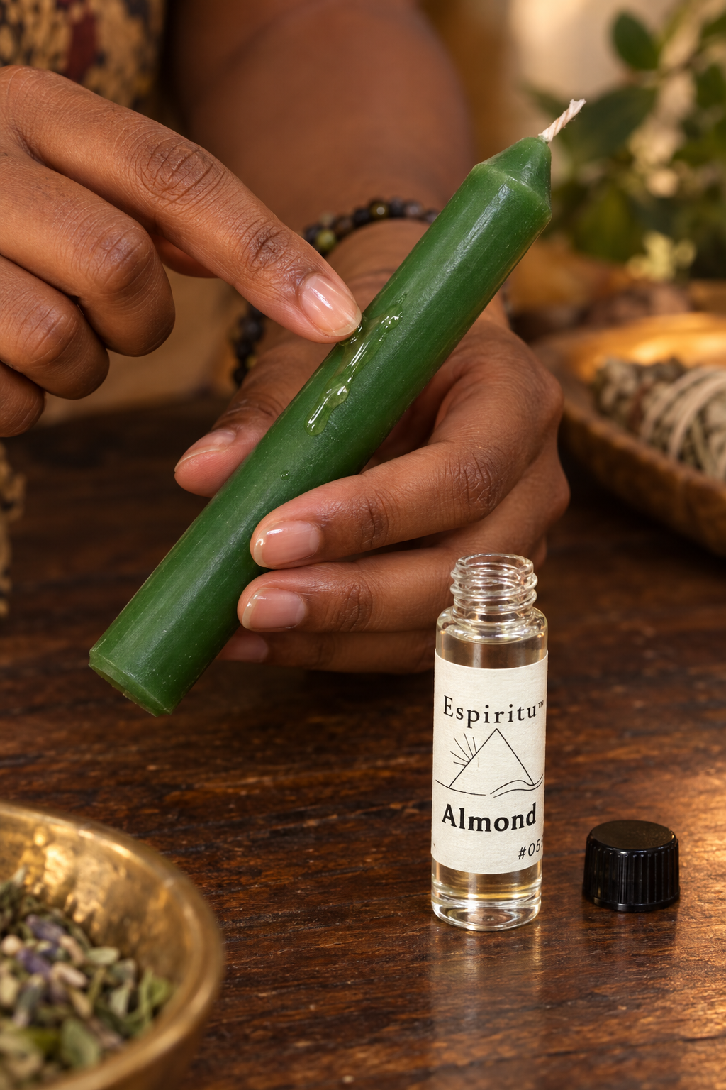 A hand dressing an unlit green candle with Espiritu Almond oil