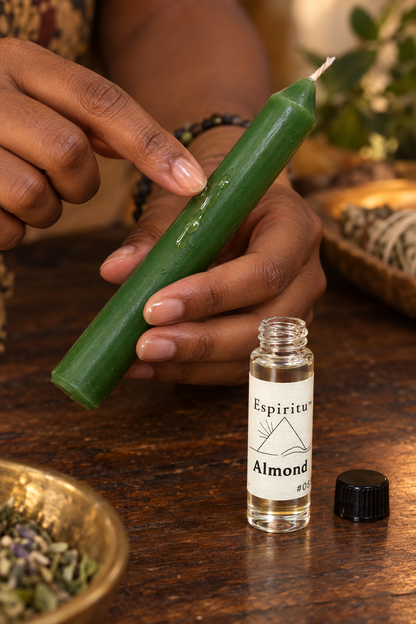 A hand dressing an unlit green candle with Espiritu Almond oil