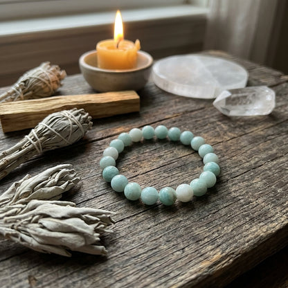 Amazonite bracelet on ritual altar with sage and candlelight, emphasizing micro-details and spiritual ambiance.