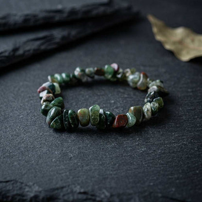 Macro shot of bloodstone bracelet on dark surface emphasizing stone textures and micro-patterns.