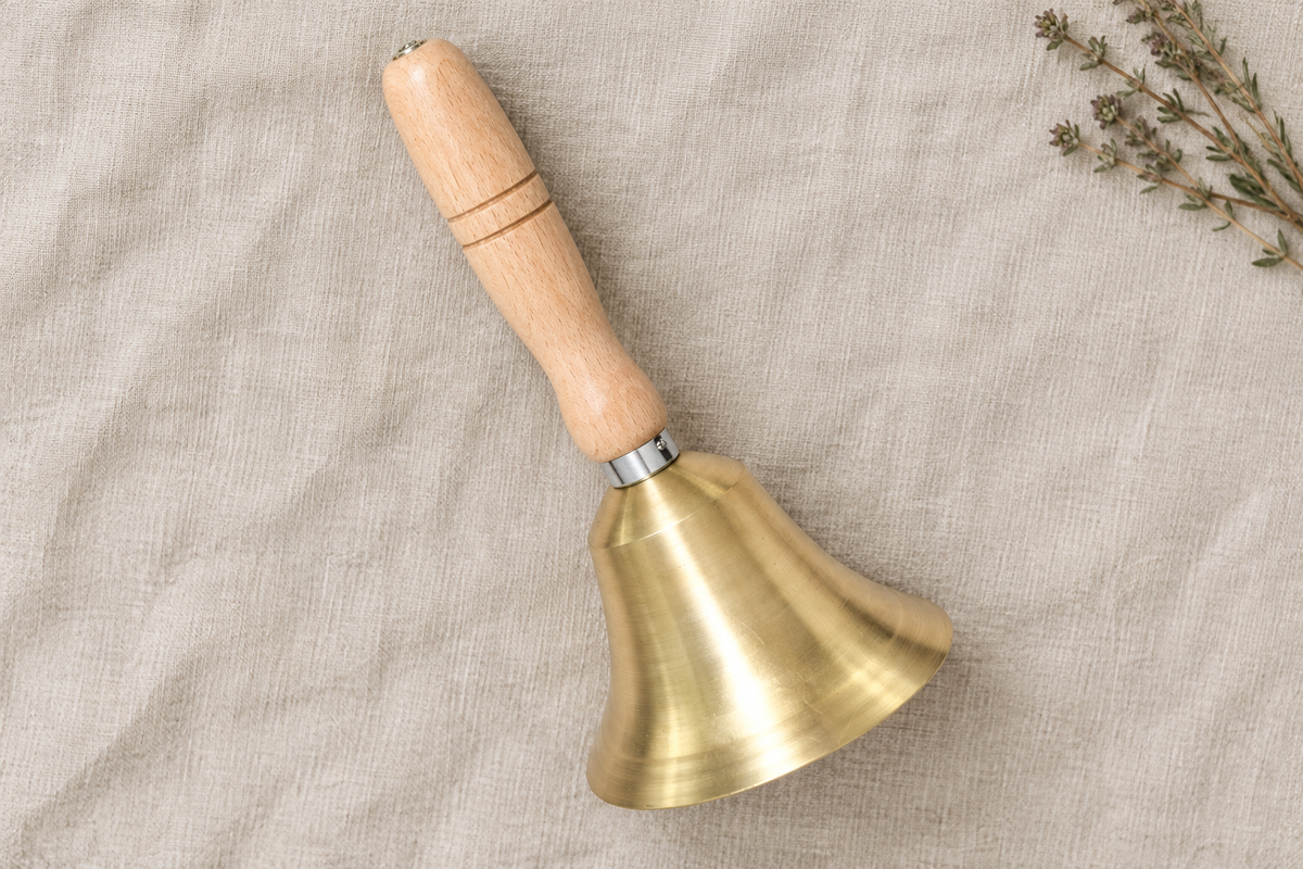 Brass hand bell flat lay on linen