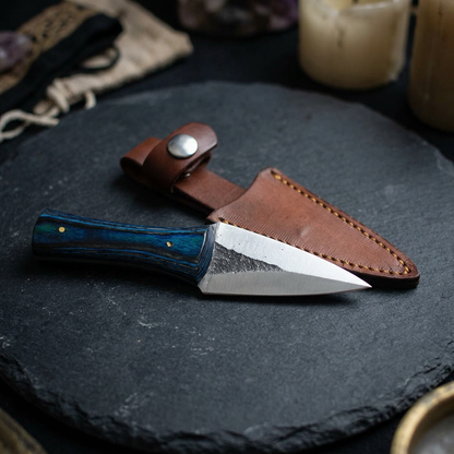 Horizontal display of a tiny arrowhead athame on dark matte surface, emphasizing blade micro-details and vibrant handle.