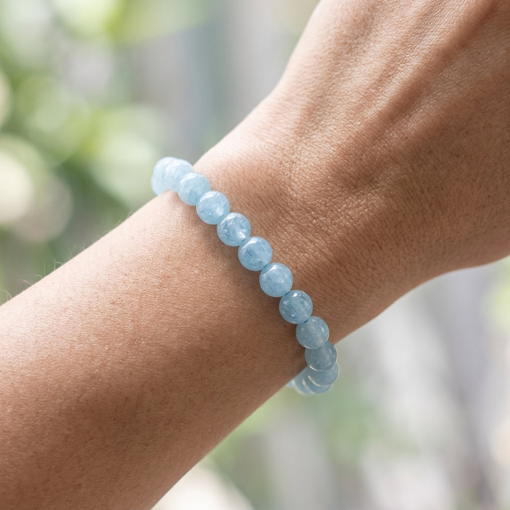 Petite aquamarine bracelet on a woman's wrist, showing tiny shimmering beads with a serene blue hue and natural background.