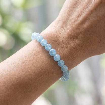 Petite aquamarine bracelet on a woman's wrist, showing tiny shimmering beads with a serene blue hue and natural background.