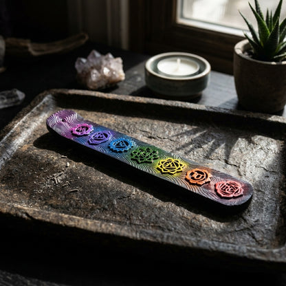 Close-up of petite Seven Chakra Incense Burner displaying detailed painted symbols on a dark stone tray with ritual setting.