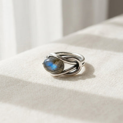 Close-up of Labradorite size 11 ring on soft fabric, illuminated by natural daylight, highlighting the iridescent gemstone and detailed silver band.