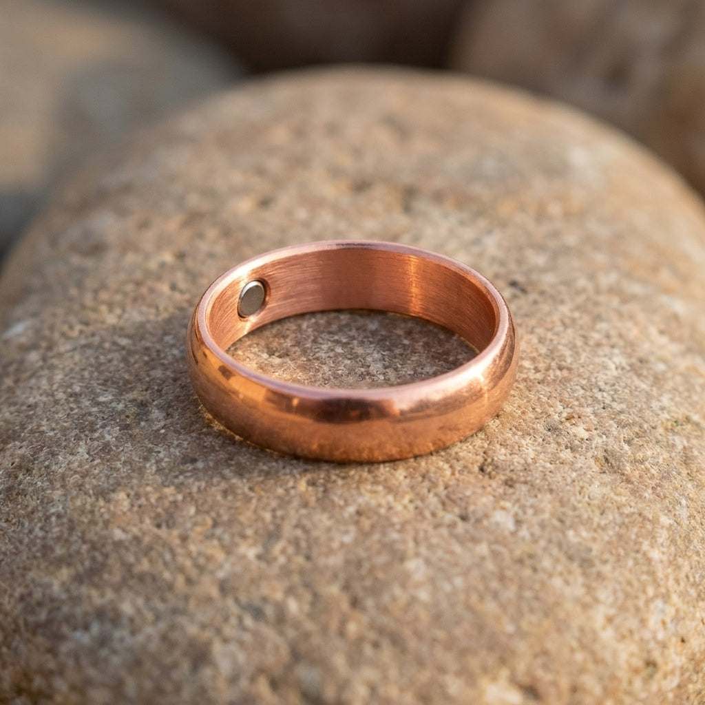 Close-up of a size 10 copper magnetic band ring on natural stone, highlighting its reddish tone and detailed texture.