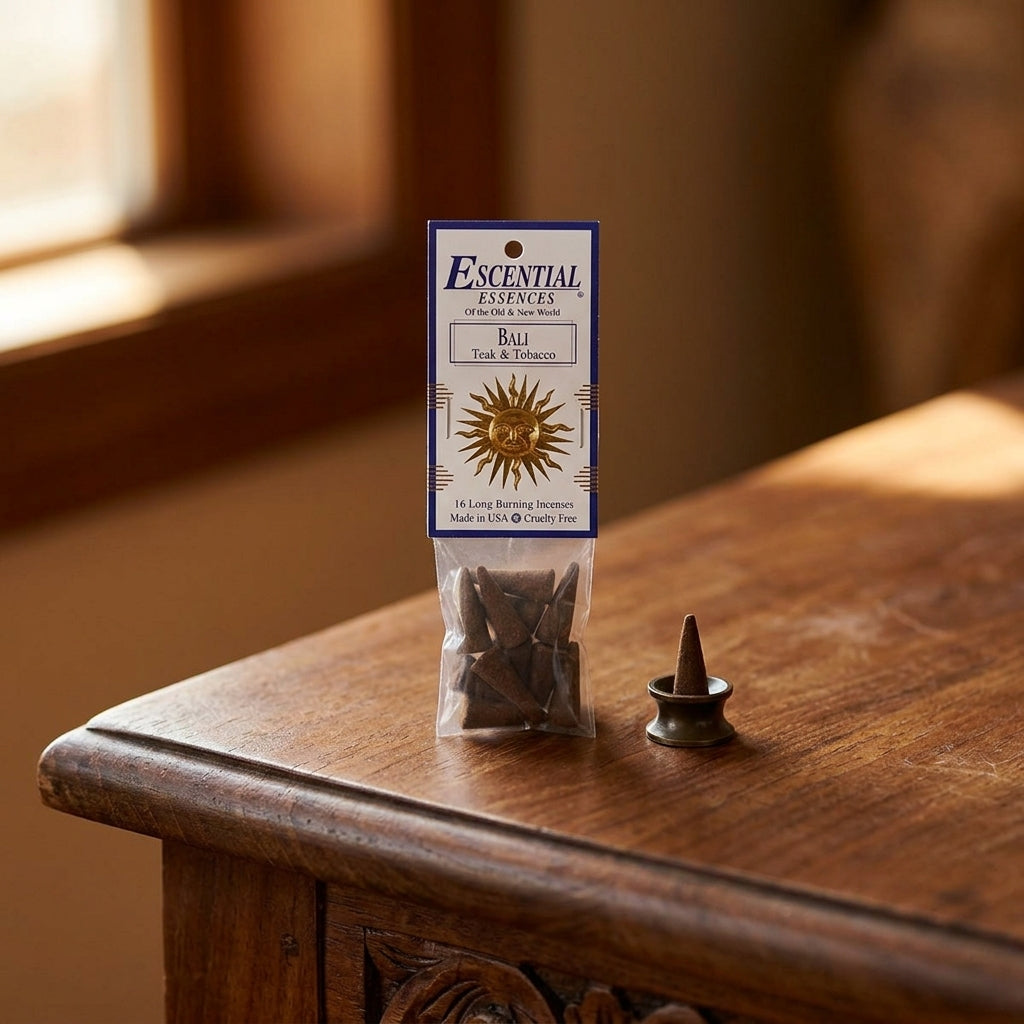 Close-up of a small Bali Teak & Tobacco incense cone resting in a stone holder on a rustic wooden surface, highlighting micro-texture and serenity.