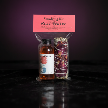 A high-resolution macro shot of the 'Rose Smudge Kit, Set of 2oz' featuring two elegantly crafted rose-scented smudge sticks resting on a reflective black velvet cloth, captured with a softbox lighting setup. The scene is lit with diffused daylight, highli