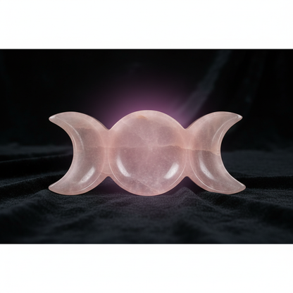 Create a highly detailed, cinematic studio shot of the Pink Calcite Triple Moon Offering Plate, 7-inch, placed on a mystical, dark velvet cloth backdrop. Use softbox lighting to gently illuminate the carved triple moon design, emphasizing the smooth, polis