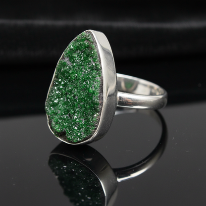 Capture a close-up, highly detailed image of the size 6 Uvarovite ring set against a sleek, dark velvet background to enhance its lustrous green hue. Use a softbox lighting setup to create gentle, diffused light that highlights the finely handcrafted sterl