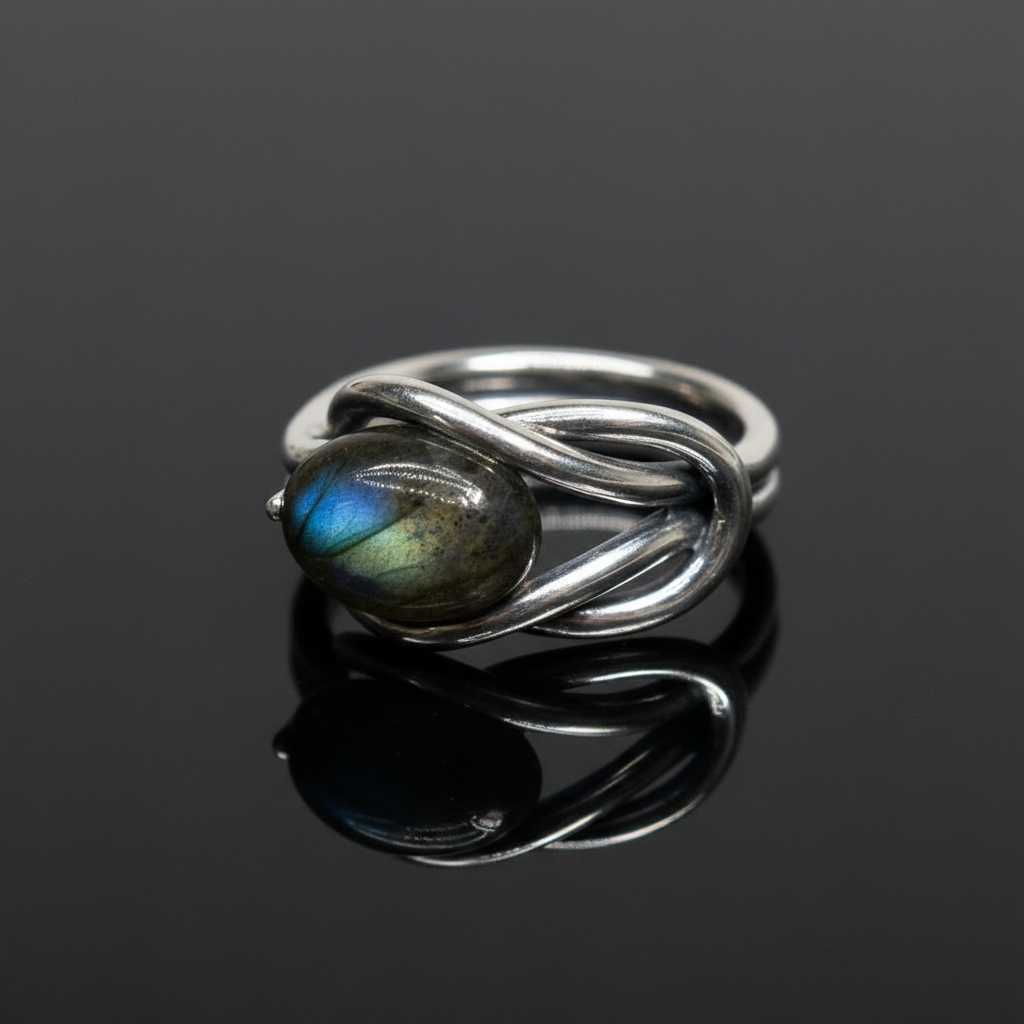 Create a highly detailed, studio-quality image of a size 12 sterling silver Labradorite ring, positioned on a sleek, reflective black surface. Use a softbox lighting setup to produce gentle, diffused daylight illumination that accentuates the iridescent fl