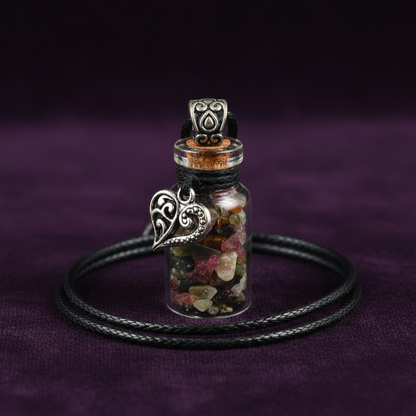 A close-up, highly detailed studio shot of the 'Torrmaline Chips in Bottle with Heart necklace,' positioned upright against a luxurious, dark velvet background to highlight its delicate craftsmanship. The scene is lit with softbox lighting to create a gent