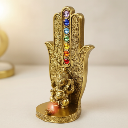 Create a highly detailed close-up shot of the Gold Ganesha Chakra Hand Incense Burner, capturing its intricate craftsmanship and radiant golden finish. Use softbox lighting to gently highlight the textured surface and the delicate carvings of Ganesha and c