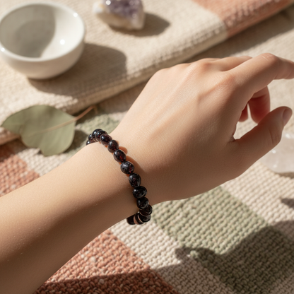  conceive an artistic lifestyle scene showcasing the 'Garnet bracelet' worn on a model's wrist in a serene, natural setting. Use diffused daylight with HDR studio lighting to evenly illuminate the bracelet, capturing the depth and vibrant color of the garn