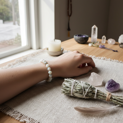 A lifestyle-inspired scene capturing the bracelet worn on a serene, relaxed wrist resting on a textured natural fiber cloth. Natural diffused daylight streams in from a nearby window, highlighting the gentle shimmer of the opal beads. The setting includes 