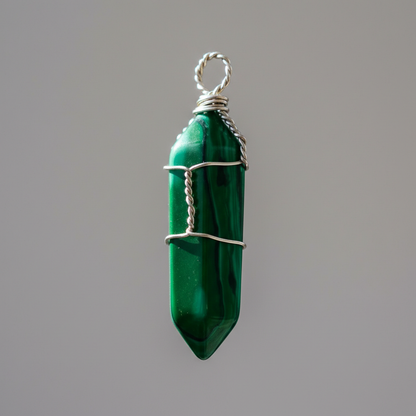 Design a dramatic, close-up macro image of a single wire wrapped synthetic Malachite point pendant suspended in mid-air, illuminated by a rim light that highlights the textured wrapping and vivid green color. Use a professional macro lens at a focal length