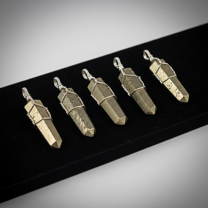 Create a highly detailed studio image of a set of five Pyrite point pendants, each approximately 1 3/8 inches long, wire-wrapped with intricate silver-toned wire that emphasizes their metallic luster. The scene is illuminated by softbox lighting to highlig