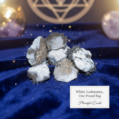 Create a serene, metaphysical scene featuring a neatly arranged collection of white lodestones on a velvet cloth inside a softly lit, elegant studio environment. Utilize softbox lighting to cast a gentle glow, enhancing the stones' smooth, polished surface