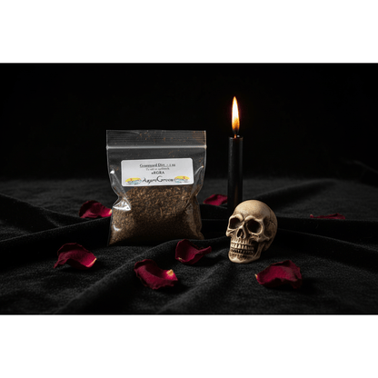 1oz resealable bag of graveyard dirt on black velvet cloth with a burning black taper candle, skull figurine, and dried rose petals
