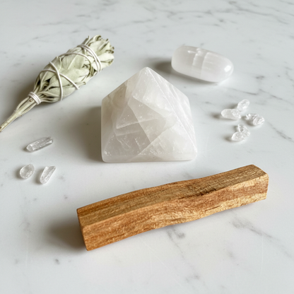 Faden Quartz Pyramid 70mm on white marble with dried sage, selenite palm stone, and scattered crystals