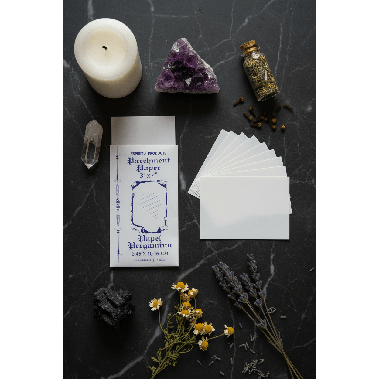 3" x 4" parchment paper sheets by Espiritu in envelope, overhead flat lay on dark marble with white pillar candle, raw amethyst, chamomile flowers, and herb bottle