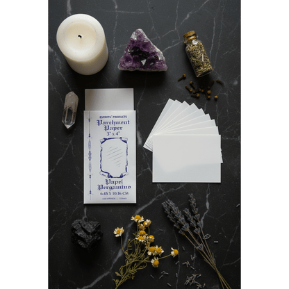 3" x 4" parchment paper sheets by Espiritu in envelope, overhead flat lay on dark marble with white pillar candle, raw amethyst, chamomile flowers, and herb bottle