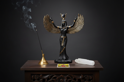 Black Hand-Painted Winged Isis Statue on a dark wooden altar shelf with incense, selenite wand, and tarot card