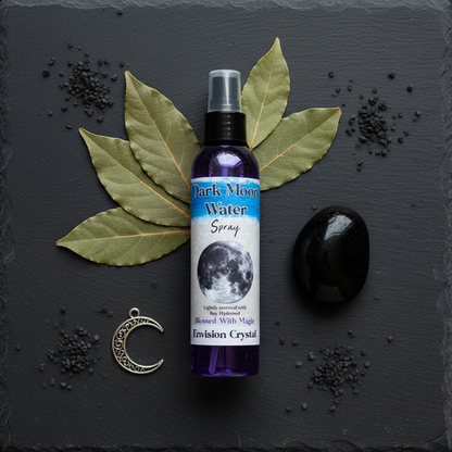 Dark Moon Water ritual spray flat lay with bay leaves, obsidian, crescent moon charm, and black salt on dark slate
