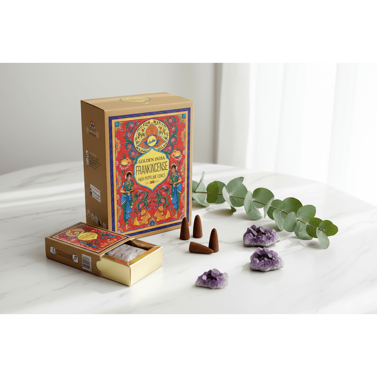 Golden India Frankincense incense cones and box on white marble with botanicals and amethyst crystals