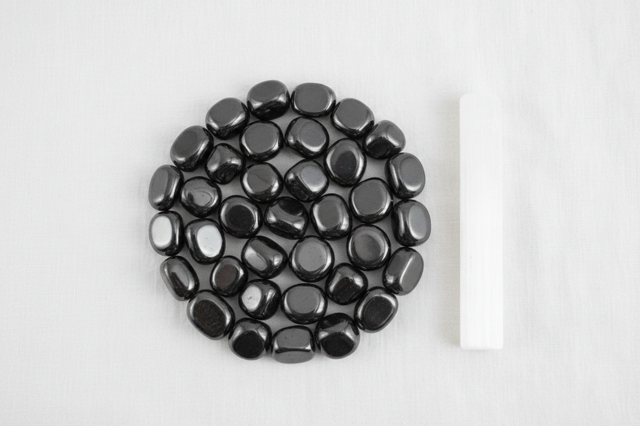 Hematite magnetic tumbled stones arranged in a crystal grid on white linen with selenite wand