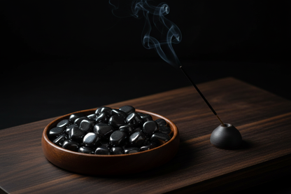 Hematite magnetic tumbled stones on dark wood altar with burning incense