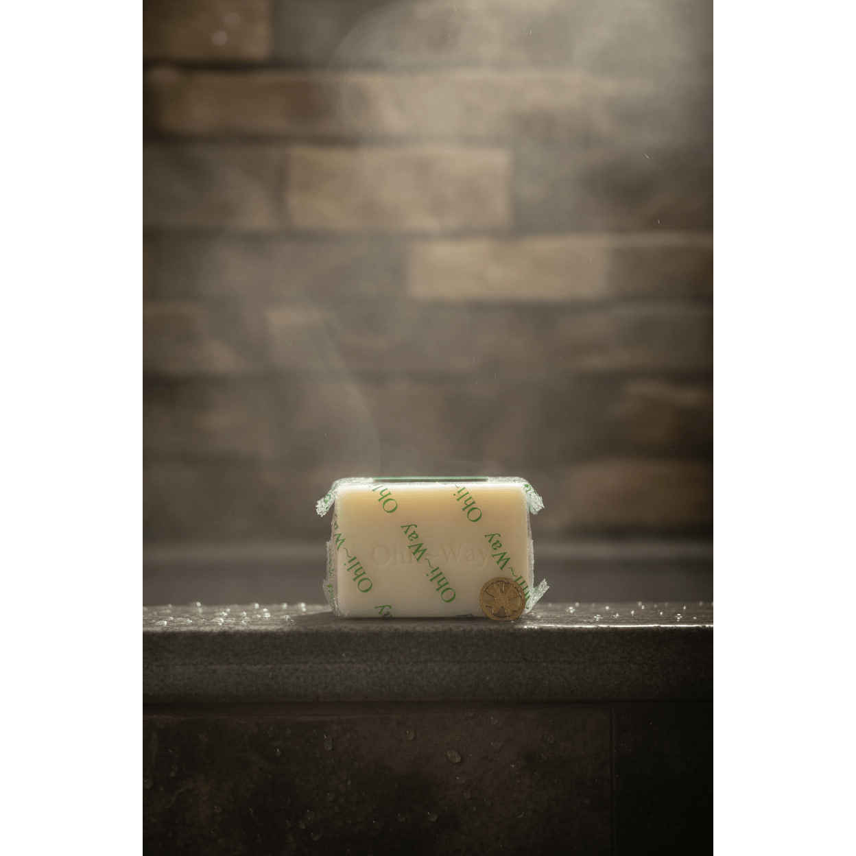 Ohli~Way Coconut Spiritual Cleansing Soap 100g bar on wet dark stone shower ledge with water droplets and soft steam