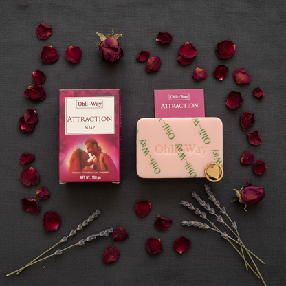 Ohli-Way Attraction Soap flat lay with pink bar, burgundy box, gold heart charm and prayer card on dark linen with dried rose petals and lavender