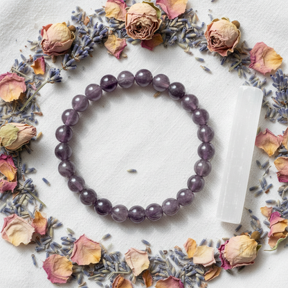 Amethyst bracelet with 8mm dusty lavender beads laid on white linen with dried lavender flowers and selenite wand
