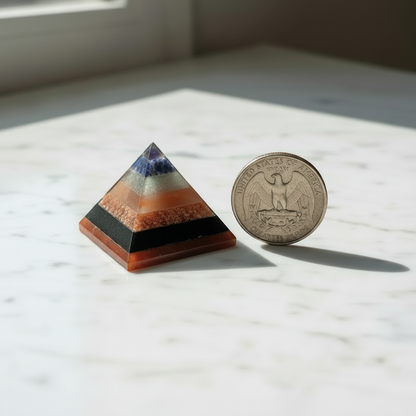 Tiny multi-layer stone pyramid beside a US quarter coin on white marble, showing true miniature scale
