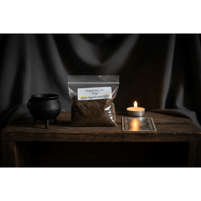 1oz resealable bag of graveyard dirt on a wooden altar shelf with a small cauldron, face-down tarot card, and lit tea light candle