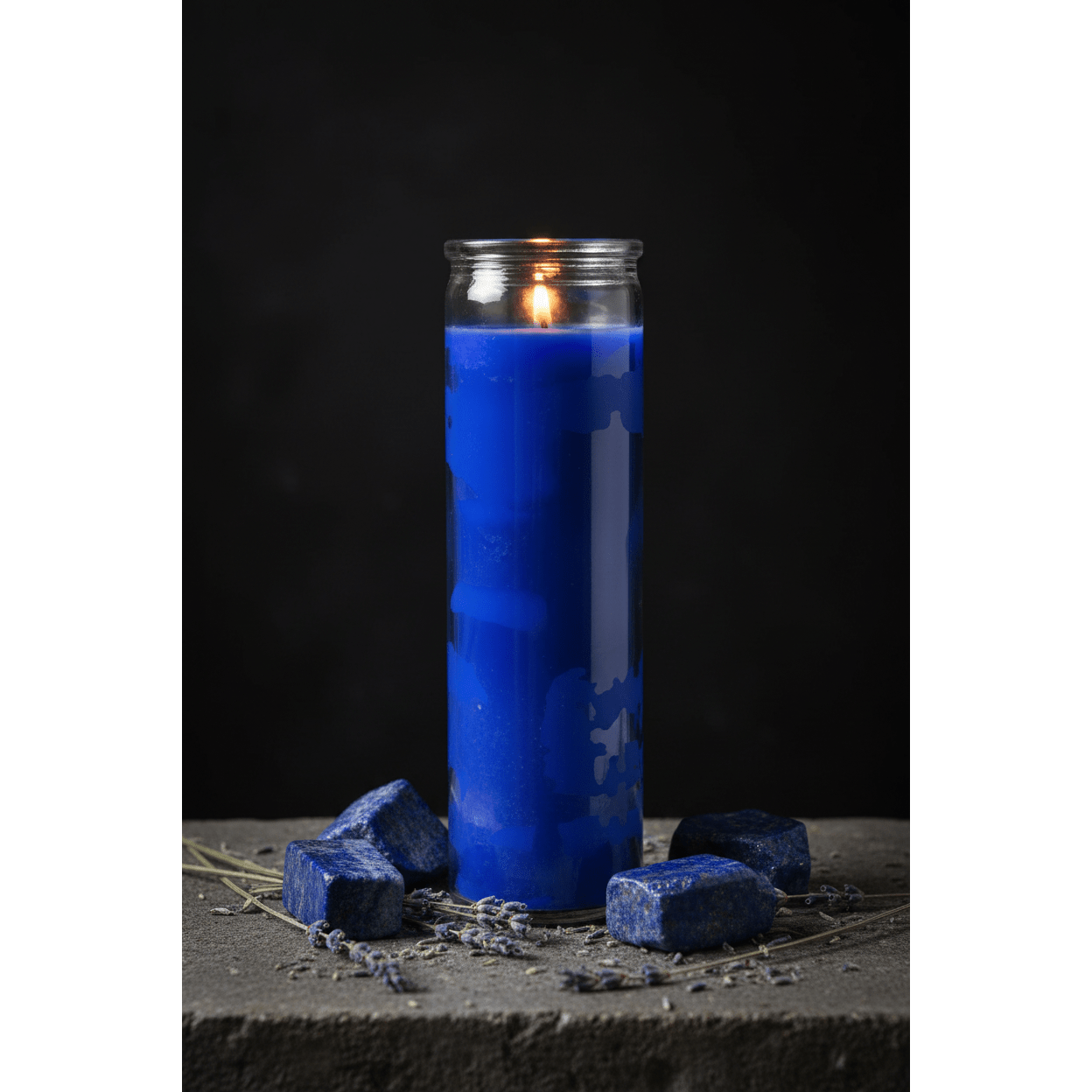 Blue 7-day jar candle surrounded by lapis lazuli crystals and dried lavender on a stone surface