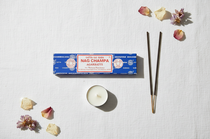 Nag Champa incense packaging with incense sticks and a candle on a light background