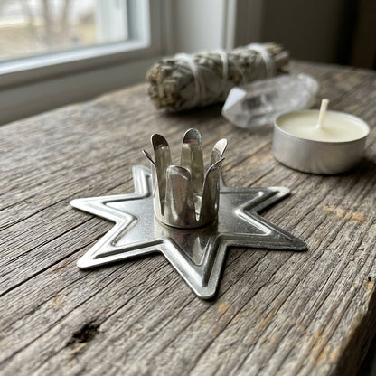 Close-up of small silver fairy star chime candle holder with intricate aluminum surface details on rustic wood background.