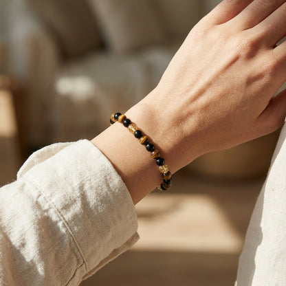 Macro image of 6mm tiger's eye, citrine, and black tourmaline beads on textured fabric, emphasizing micro-texture and craftsmanship.