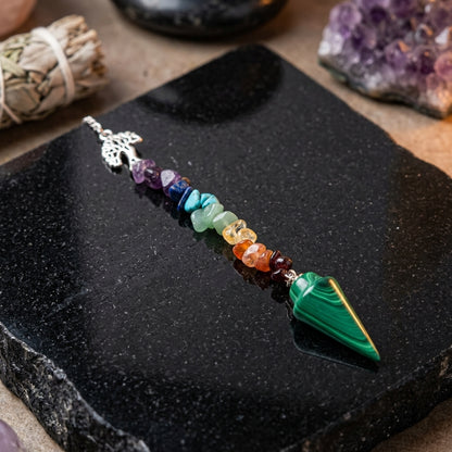 Close-up of Malachite Tree Chakra Pendulum on black stone, emphasizing smooth polish and detailed green swirls.