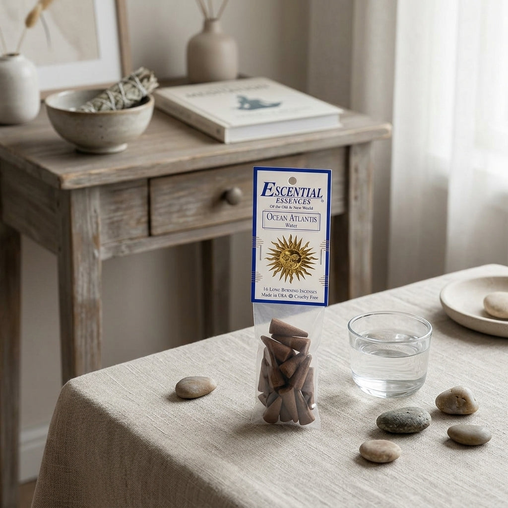 Close-up of small incense cone next to water glass on textured fabric, in calm, minimalist spiritual workspace.