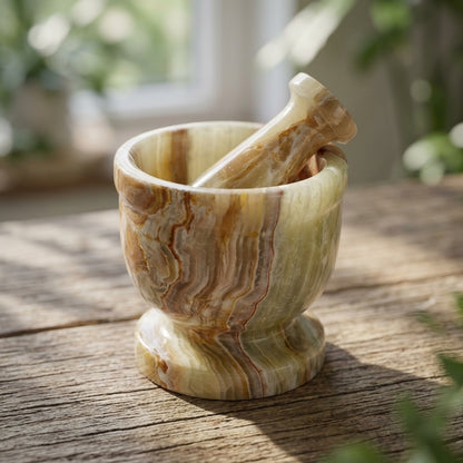Close-up of a small onyx mortar and pestle set with natural striations, resting on wooden surface in natural light.