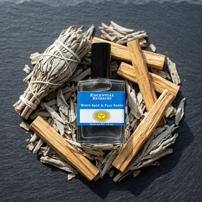 Overhead shot of a 1/2oz white sage and Palo Santo oil bottle on dried herbs and wood sticks on a dark stone surface.
