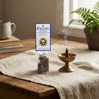 Close-up of small Paris Cafe incense cone in brass burner on linen cloth with serene decor.